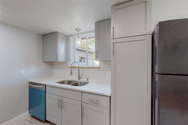 kitchen featuring stainless steel appliances, hanging light fixtures, a textured ceiling, sink, and backsplash