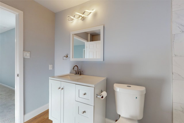 bathroom with toilet, vanity, and wood-type flooring