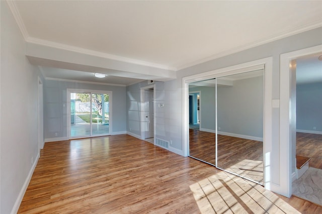 unfurnished bedroom with a closet, ornamental molding, and light hardwood / wood-style flooring