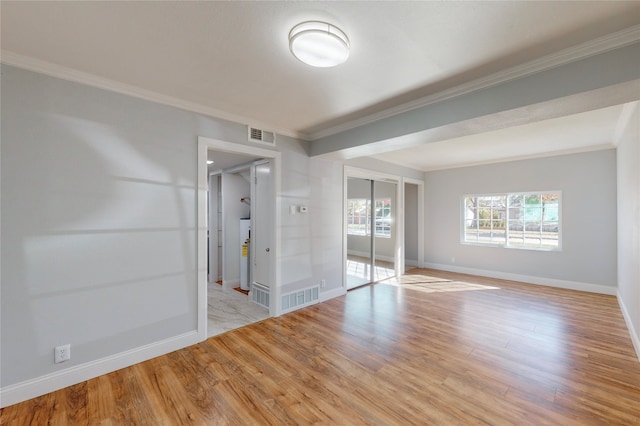 spare room featuring water heater, light wood-type flooring, and crown molding