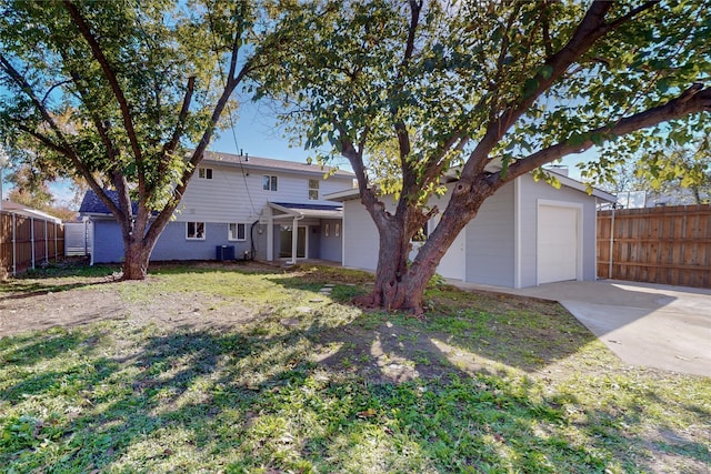 rear view of property featuring central AC, a garage, and a lawn