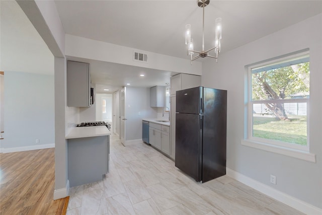 kitchen featuring stainless steel appliances, a notable chandelier, hanging light fixtures, sink, and gray cabinetry