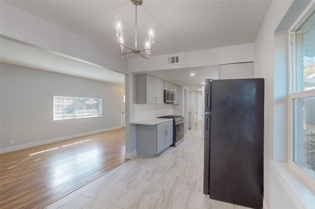 kitchen featuring stainless steel appliances, backsplash, a chandelier, light hardwood / wood-style flooring, and gray cabinetry