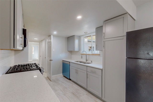 kitchen featuring sink, light stone counters, appliances with stainless steel finishes, tasteful backsplash, and gray cabinets