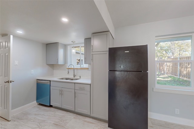 kitchen featuring black fridge, sink, plenty of natural light, stainless steel dishwasher, and gray cabinetry