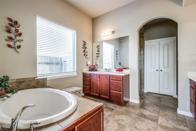 bathroom featuring vanity, a relaxing tiled tub, and tile patterned flooring