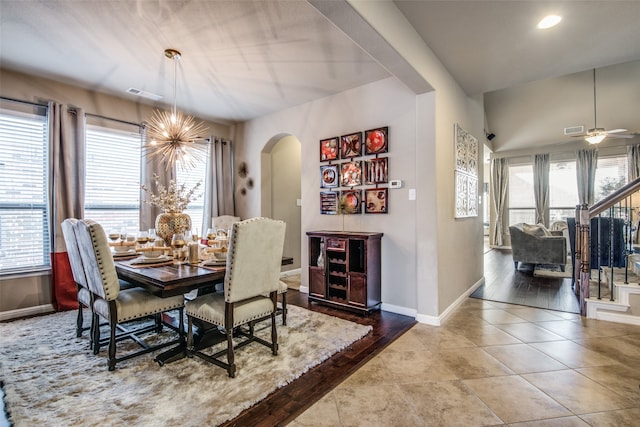 dining area featuring vaulted ceiling, wood-type flooring, and ceiling fan with notable chandelier