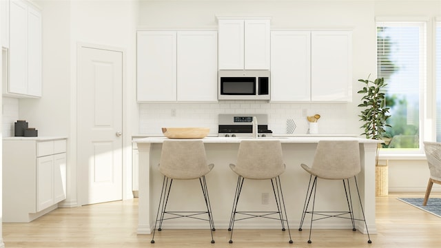 kitchen featuring white cabinetry, range, and a center island with sink