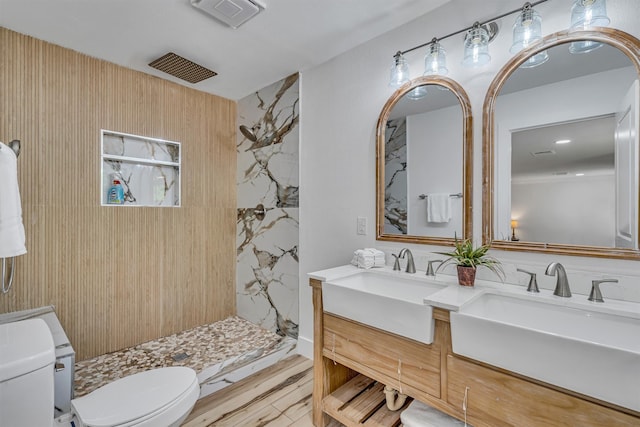 bathroom with toilet, vanity, hardwood / wood-style flooring, and a tile shower