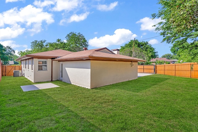 back of property with central AC and a yard