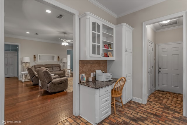 kitchen with built in desk, tasteful backsplash, white cabinetry, ceiling fan, and crown molding