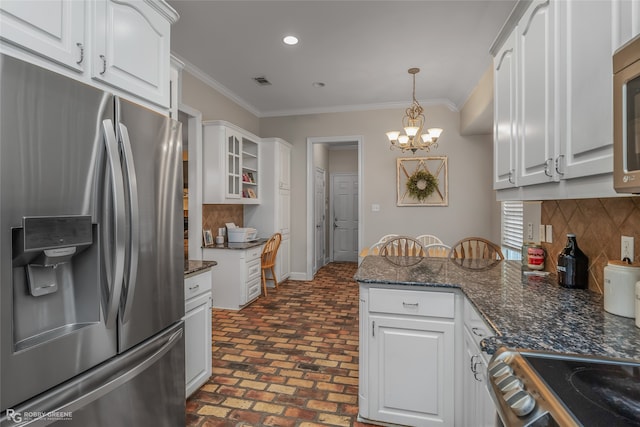 kitchen with white cabinets, dark stone counters, hanging light fixtures, stainless steel appliances, and crown molding