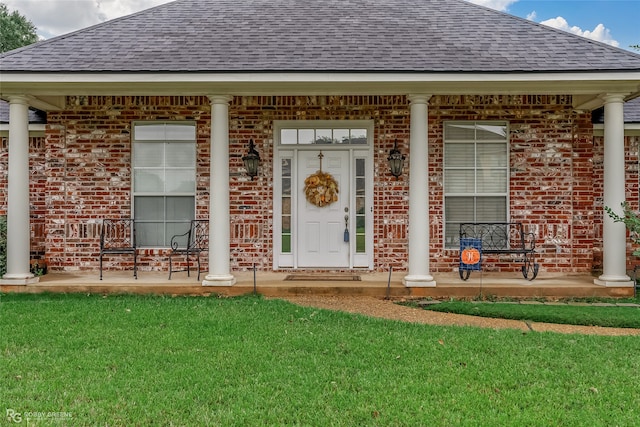 entrance to property featuring a porch and a lawn