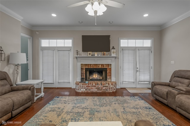 living room featuring ornamental molding, a healthy amount of sunlight, a fireplace, and dark hardwood / wood-style flooring