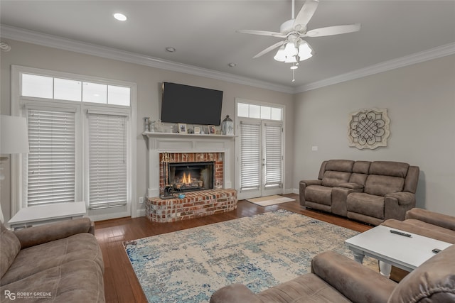 living room with dark hardwood / wood-style floors, ceiling fan, ornamental molding, and a fireplace