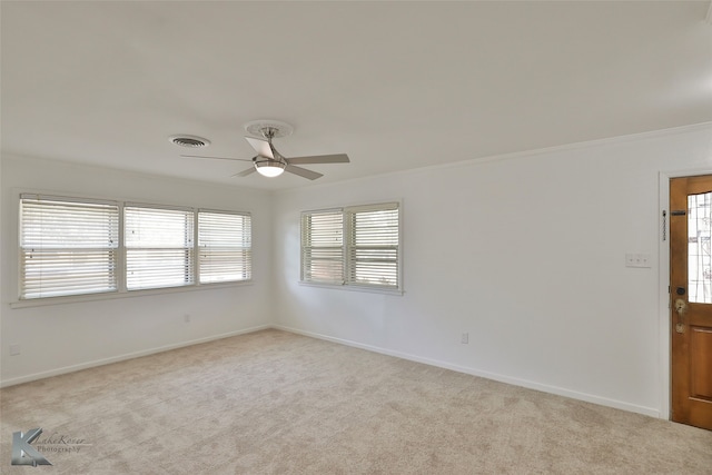 carpeted empty room featuring ornamental molding, a wealth of natural light, and ceiling fan