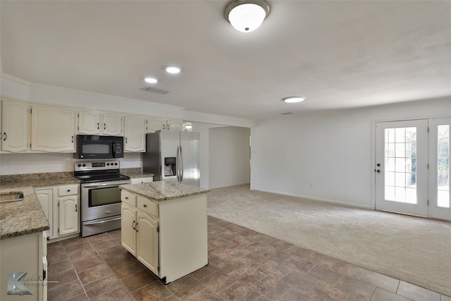 kitchen featuring dark colored carpet, stainless steel appliances, a kitchen island, and light stone countertops