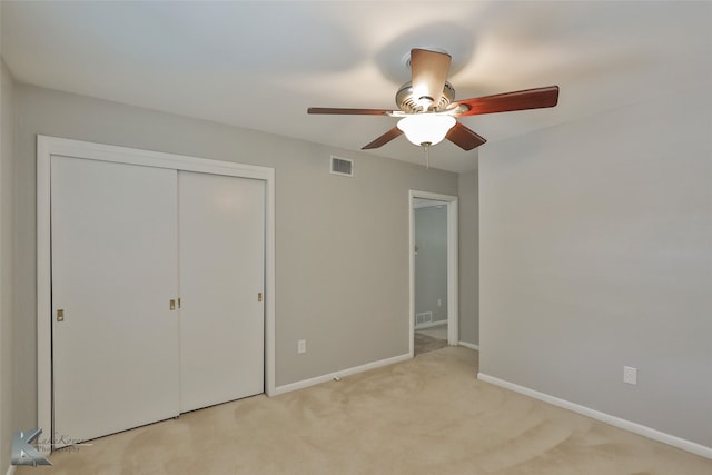 unfurnished bedroom featuring ceiling fan, a closet, and light carpet