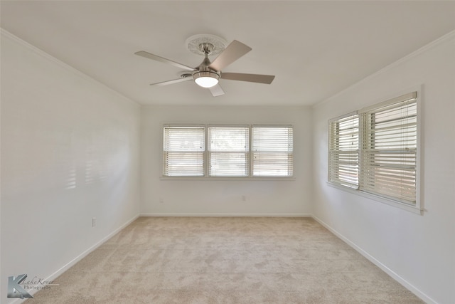 carpeted spare room with ceiling fan, ornamental molding, and plenty of natural light