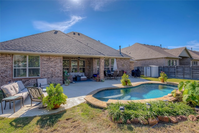 view of pool featuring outdoor lounge area, a patio, and a storage shed