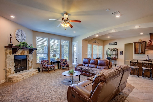 tiled living room featuring a fireplace, ceiling fan, and sink