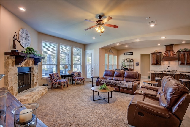 living room featuring a fireplace, light colored carpet, ceiling fan, and a healthy amount of sunlight