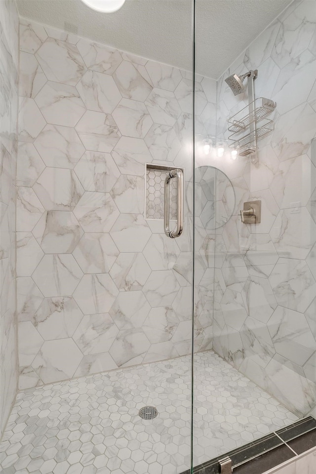 bathroom with a shower with shower door and a textured ceiling