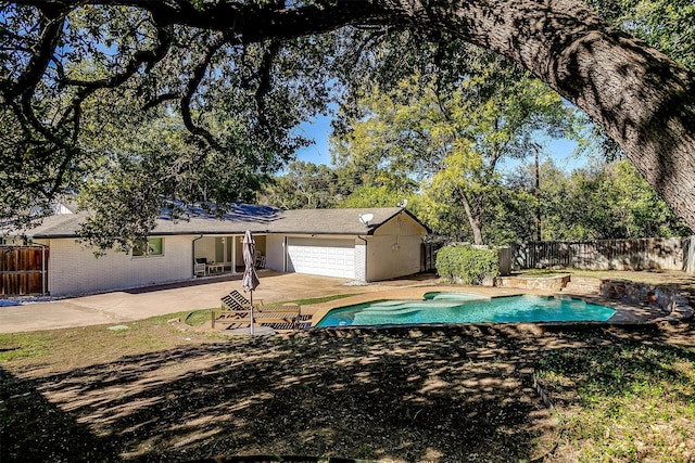 exterior space featuring a garage, a swimming pool with hot tub, and a patio area