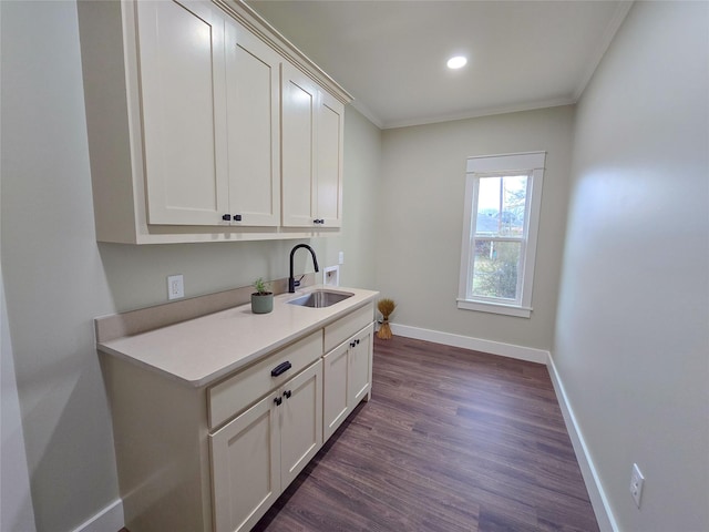 clothes washing area featuring washer hookup, cabinet space, dark wood-type flooring, a sink, and baseboards