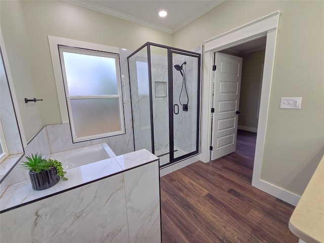 bathroom featuring a garden tub, a marble finish shower, ornamental molding, wood finished floors, and baseboards