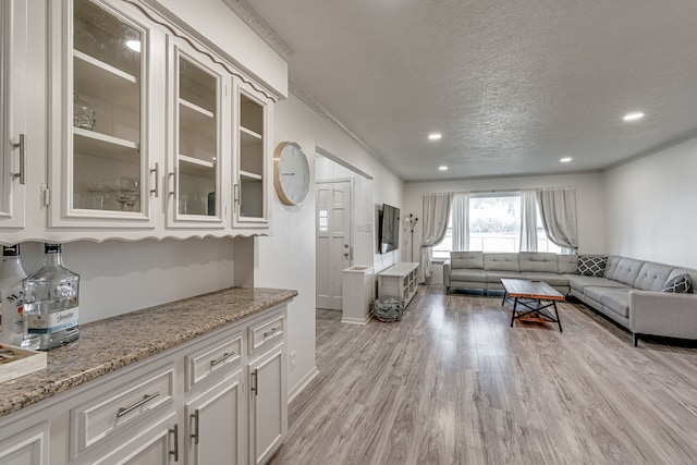 living room with a textured ceiling, crown molding, and light hardwood / wood-style flooring