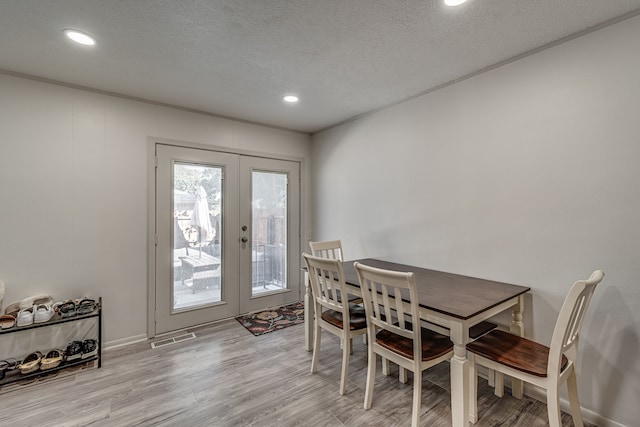 dining space featuring a textured ceiling, french doors, and light hardwood / wood-style flooring