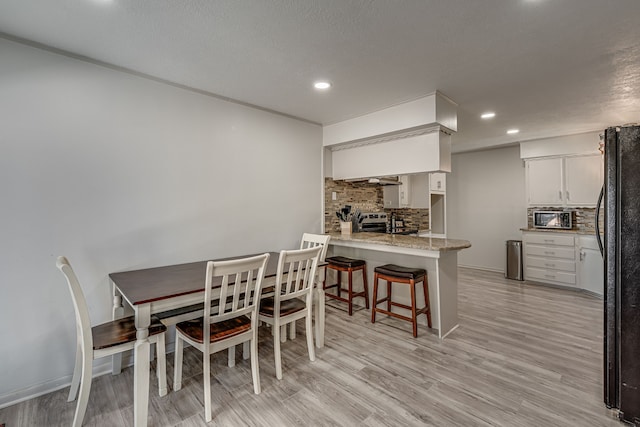 dining room featuring light wood-type flooring and a textured ceiling