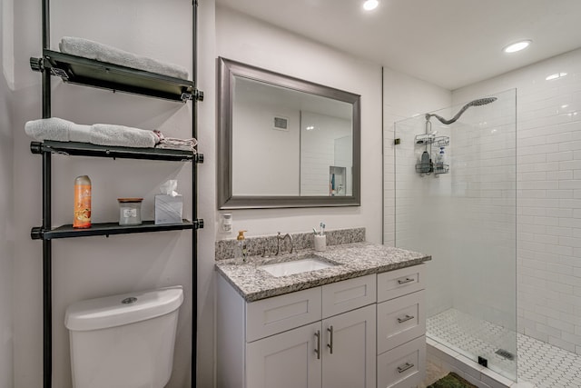 bathroom featuring toilet, vanity, and tiled shower