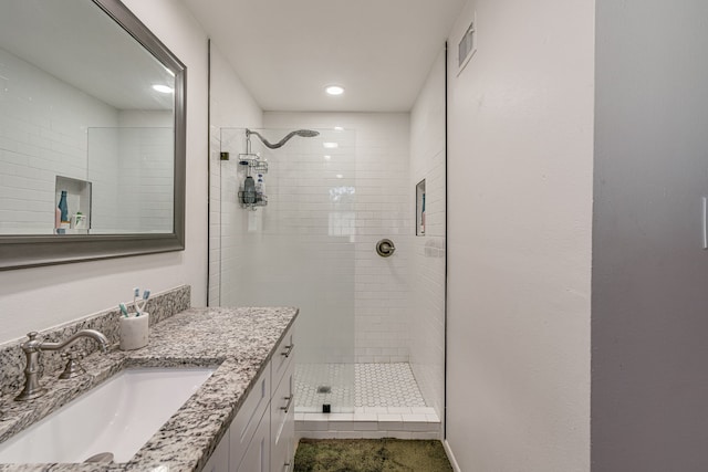 bathroom featuring tile patterned flooring, tiled shower, and vanity