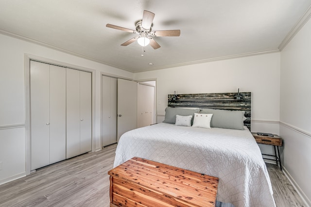 bedroom with crown molding, two closets, ceiling fan, and light wood-type flooring