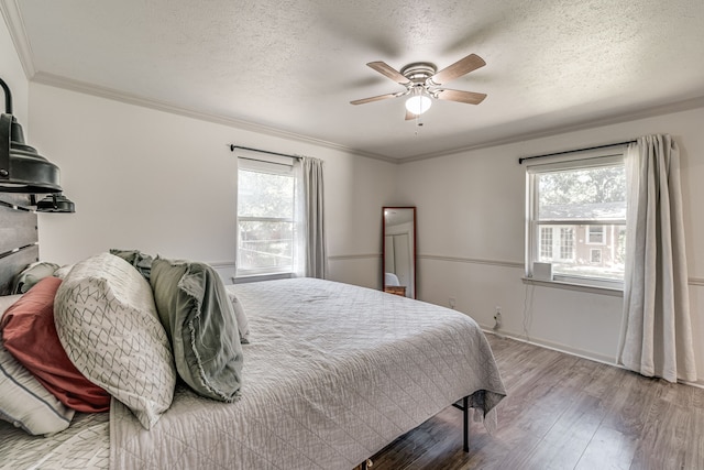 bedroom featuring hardwood / wood-style flooring, ceiling fan, multiple windows, and a textured ceiling