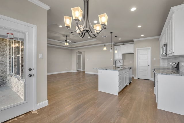 kitchen with white cabinets, sink, hanging light fixtures, an island with sink, and tasteful backsplash