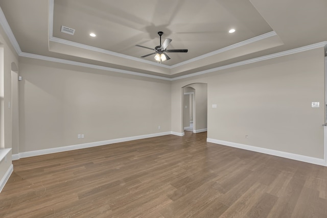 spare room with a tray ceiling, hardwood / wood-style flooring, ornamental molding, and ceiling fan