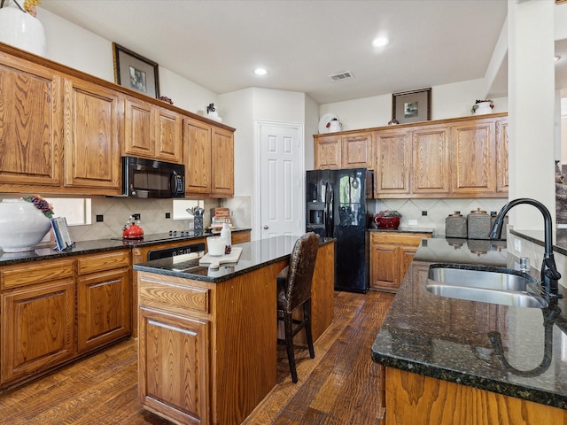 kitchen with dark stone countertops, sink, black appliances, and a center island