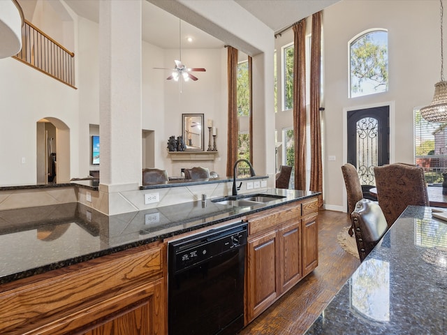 kitchen featuring sink, dark hardwood / wood-style floors, black dishwasher, pendant lighting, and dark stone counters