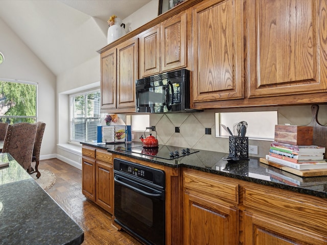 kitchen with tasteful backsplash, black appliances, dark stone countertops, and lofted ceiling