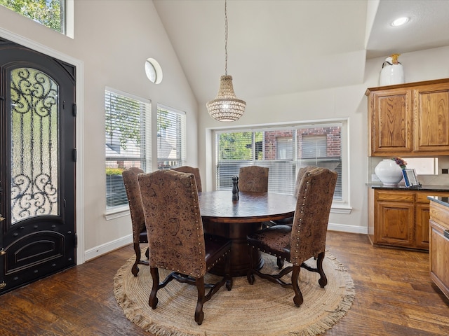 dining space featuring dark hardwood / wood-style flooring, high vaulted ceiling, and a chandelier