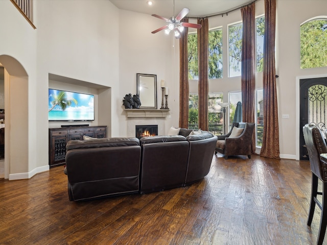 living room with a healthy amount of sunlight, a towering ceiling, and dark wood-type flooring