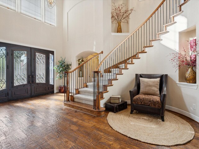 stairs with wood-type flooring and a high ceiling