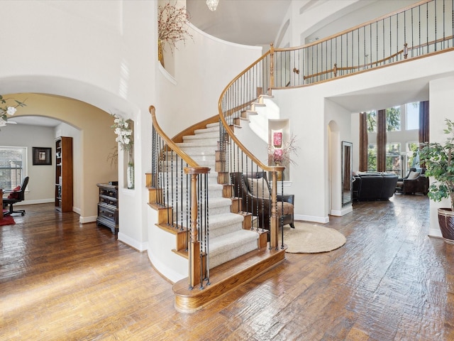 stairs with a high ceiling, wood-type flooring, and a wealth of natural light