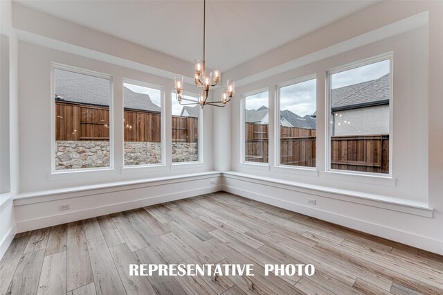 unfurnished dining area featuring light wood-type flooring and a notable chandelier