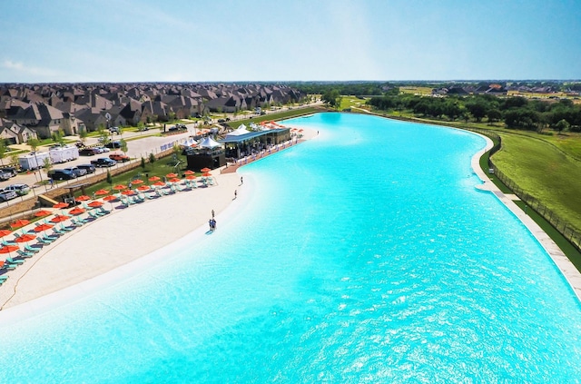 view of swimming pool featuring a water view and a beach view