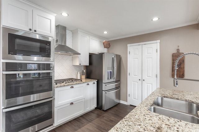 kitchen with white cabinets, wall chimney range hood, sink, and appliances with stainless steel finishes