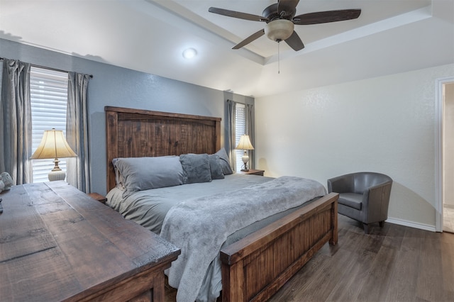 bedroom with a raised ceiling, ceiling fan, and dark hardwood / wood-style floors